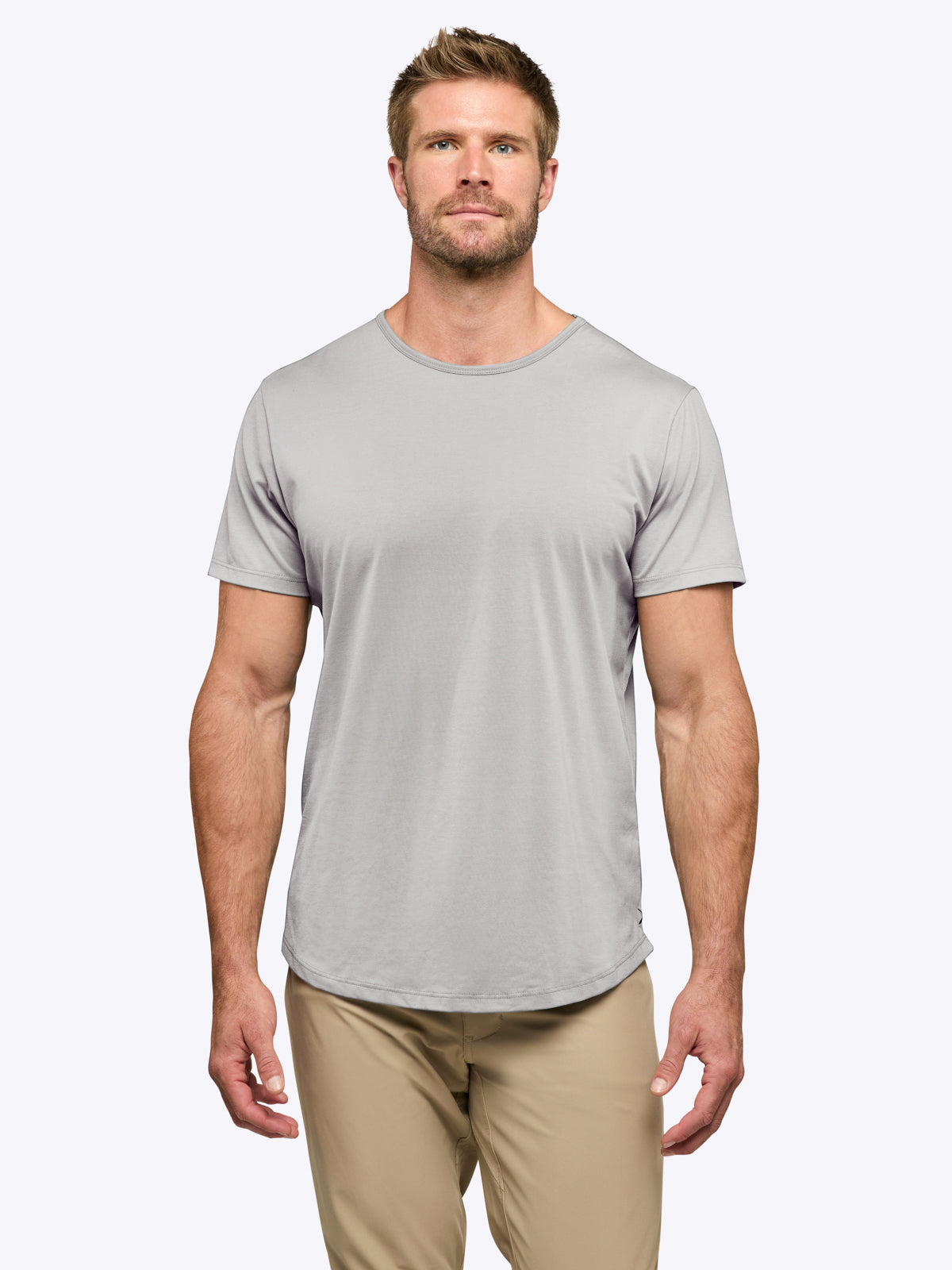 Man wearing a gray t-shirt and beige pants on a white background