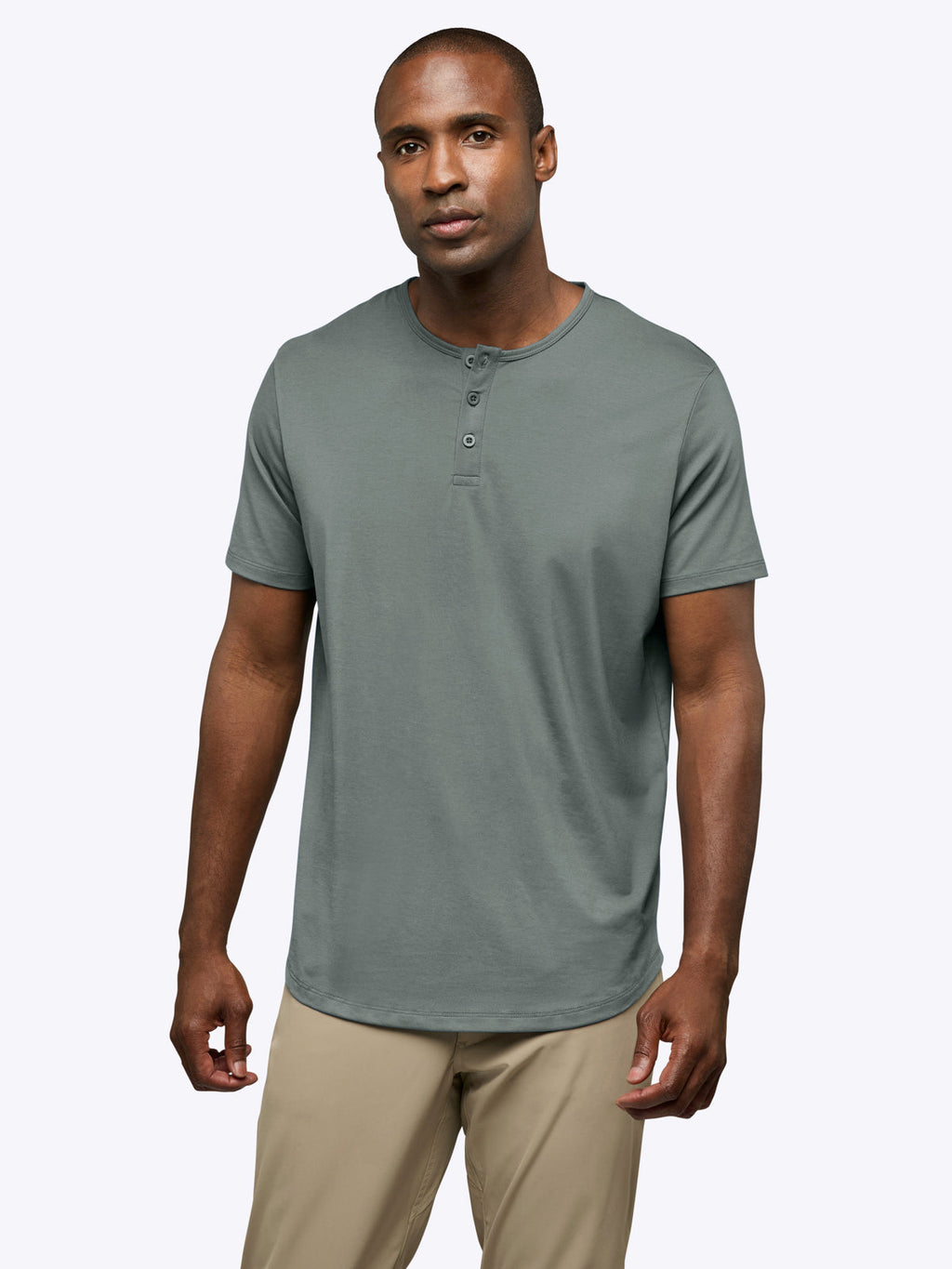Man wearing a gray henley shirt and beige pants on a white background