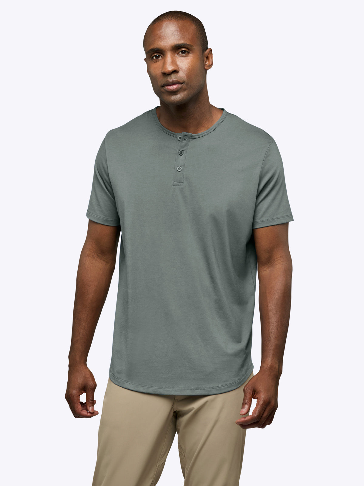 Man wearing a gray henley shirt and beige pants on a white background