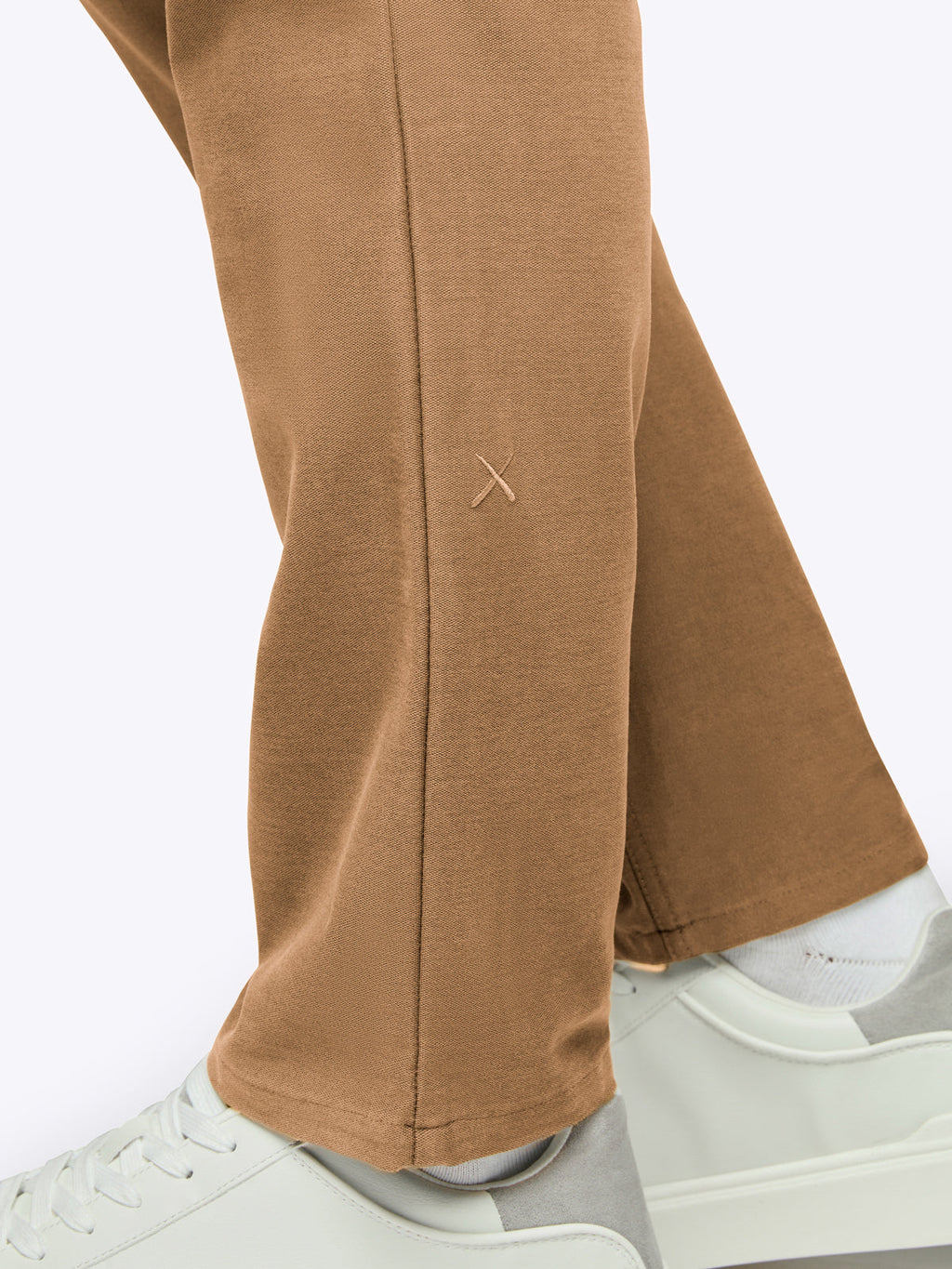 Brown pants worn with white sneakers on a white background